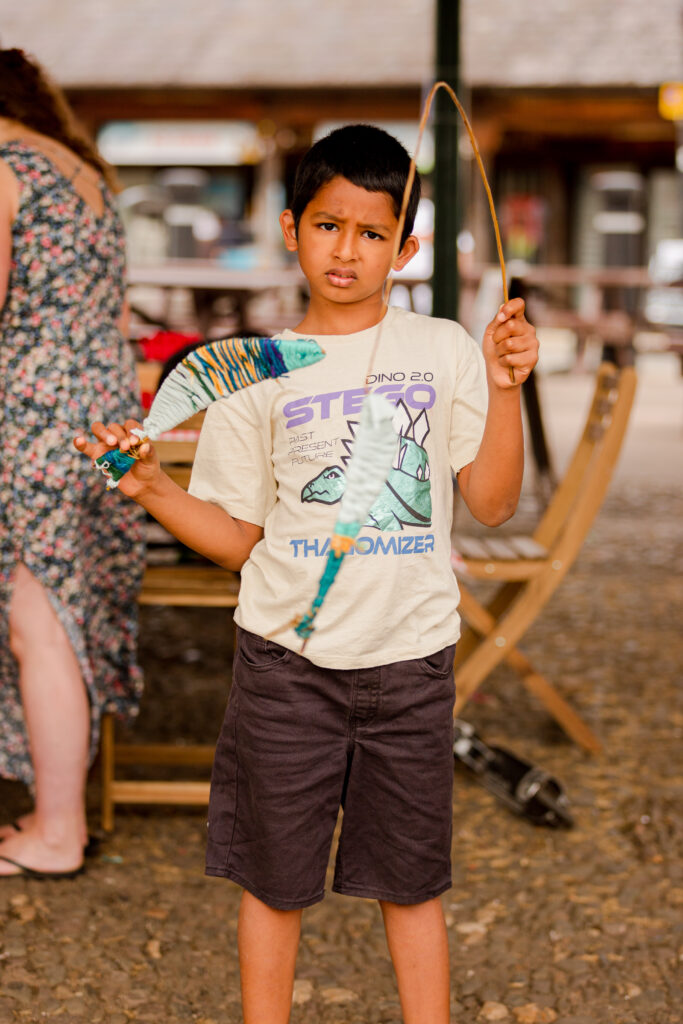 Young boy displaying his willow and wool fish on a fishing rod at the Weird Sticks workshop, Exeter Quay