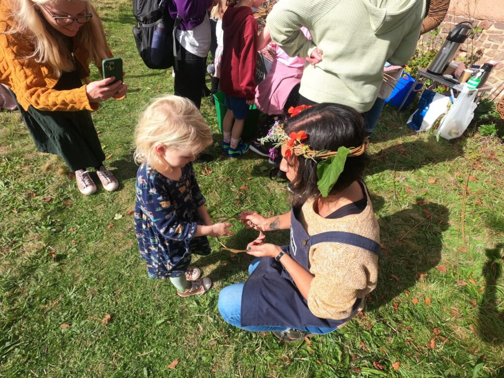Hannah from Weird Sticks working with a small child to weave a willow harvest crown