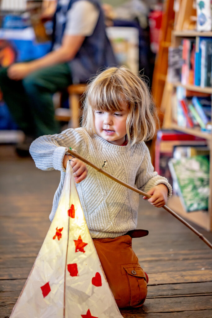 Child holding their completed lanterns at the Weird Sticks Exeter Carnival Lantern Workshop at Boston Tea Party