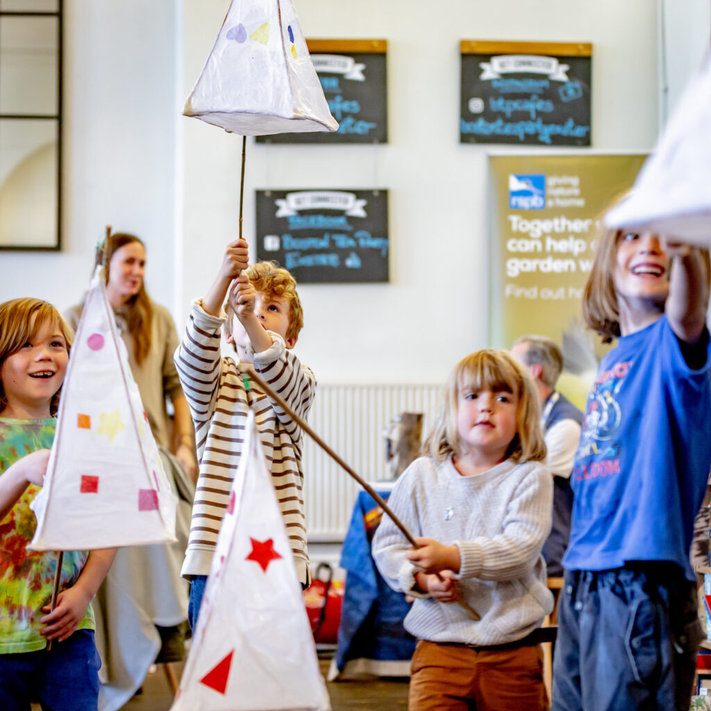 Children holding their completed lanterns at the Weird Sticks Exeter Carnival Lantern Workshop at Boston Tea Party