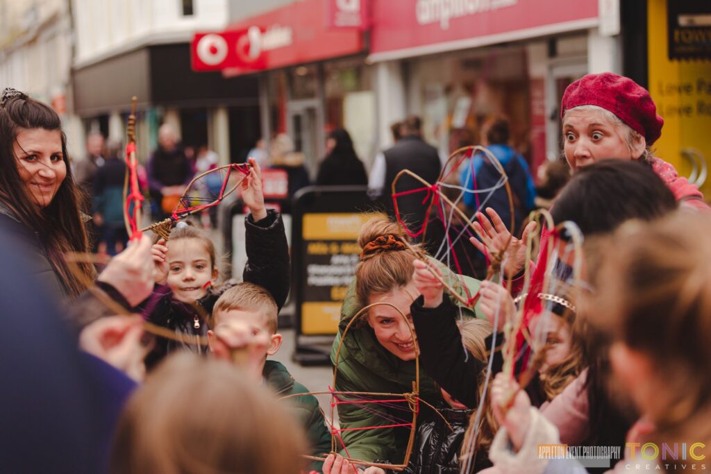 Families weaving their willow and wool creations at the Weird Sticks workshops in Torbay at Playing in the Streets 2023