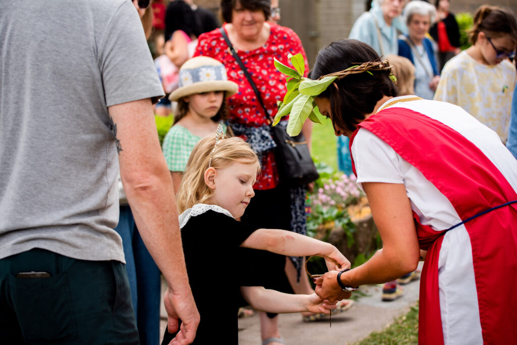 Hannah from Weird Sticks working with a child to weave a Roman willow and laurel crown at the Cullompton Roman Festival