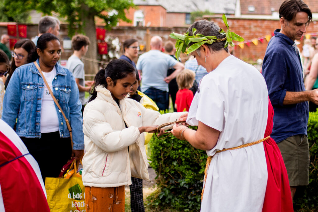 Vik from Weird Sticks working with a child to weave a Roman willow and laurel crown at the Cullompton Roman Festival