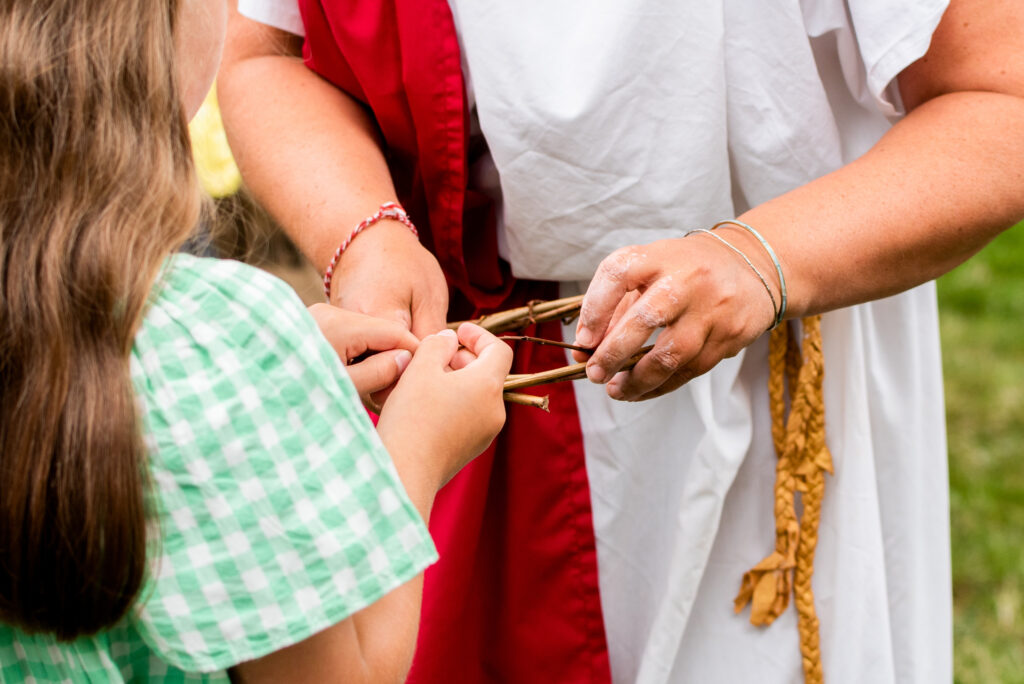 Child creating a Roman willow and laurel crown with Weird Sticks at the Cullompton Roman Festival