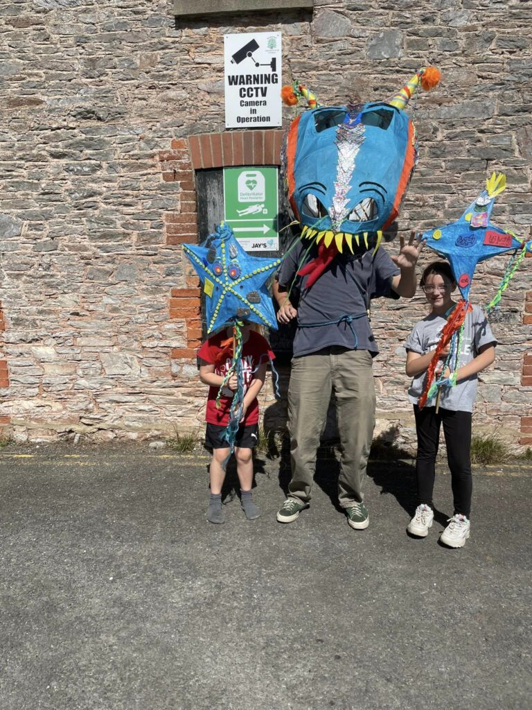Adult and two children displaying some parade puppets created with Weird Sticks at Play Torbay