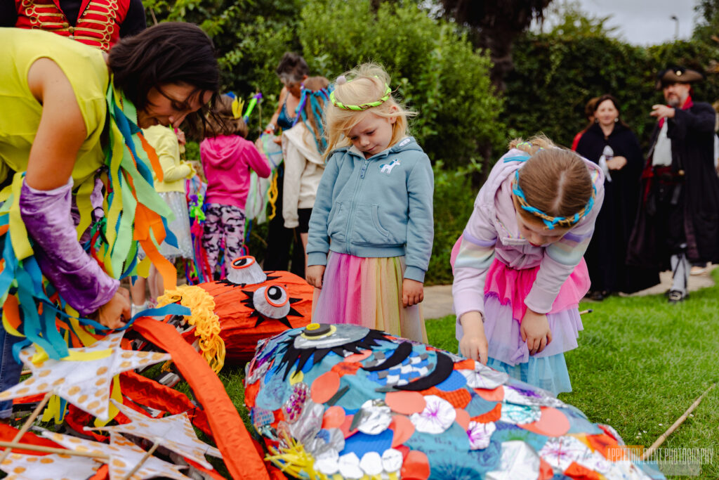 Hannah from Weird Sticks helping two children to assemble a giant octopus parade puppet for the Exmouth Festival parade