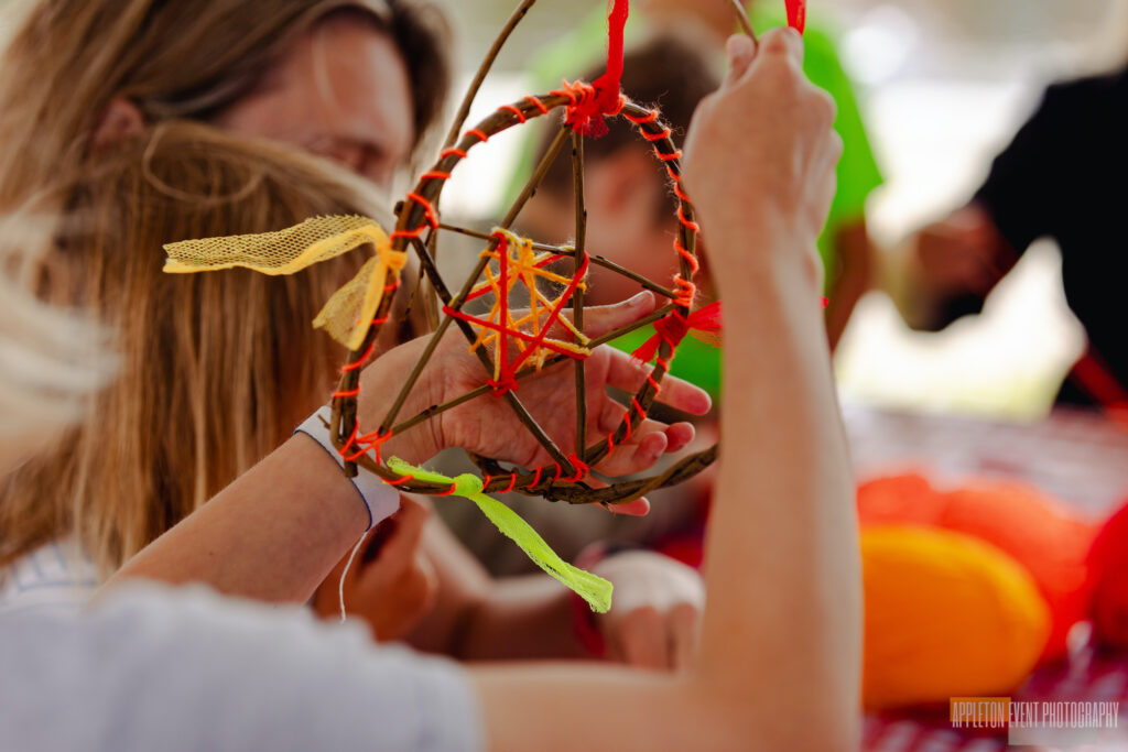 Child weaving wool into their willow spinning sun creation at the Weird Sticks workshop, Exeter Quay