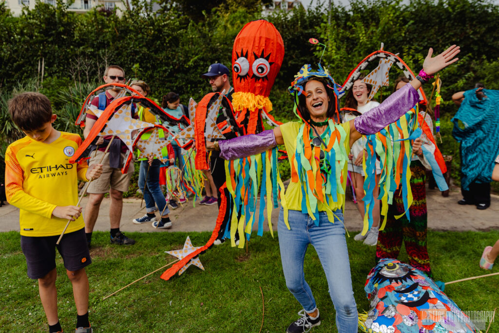 Hannah from Weird Sticks poses with parade participants carrying the giant octopus puppet creation at Exmouth Festival samba parade