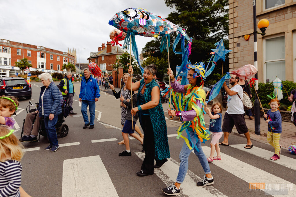Giant fish parade puppet made by Weird Sticks being carried as part of the Exmouth Festival samba parade