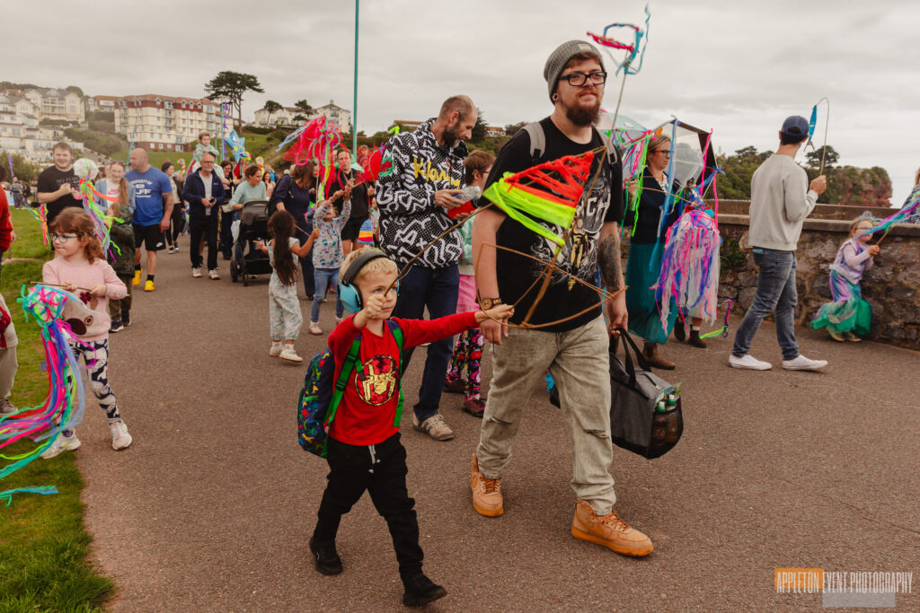Goodrington Seafest parade participants carrying their parade crafts created with Weird Sticks