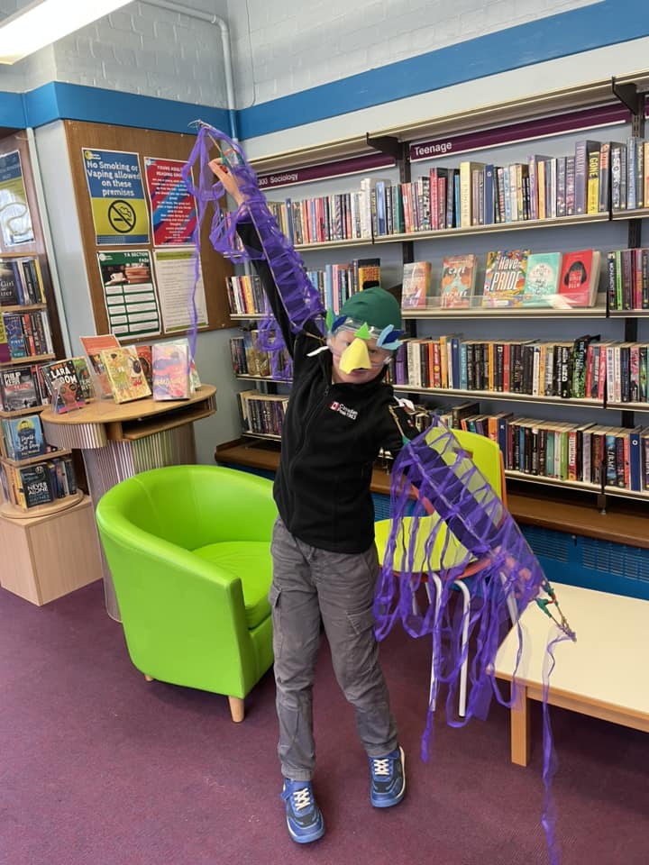 Child wearing their space-themed creations at the Weird Sticks workshop at Exmouth Library for Exmouth Festival 2024