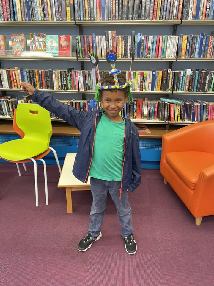 Child wearing their space-themed creations at the Weird Sticks workshop at Exmouth Library for Exmouth Festival 2024