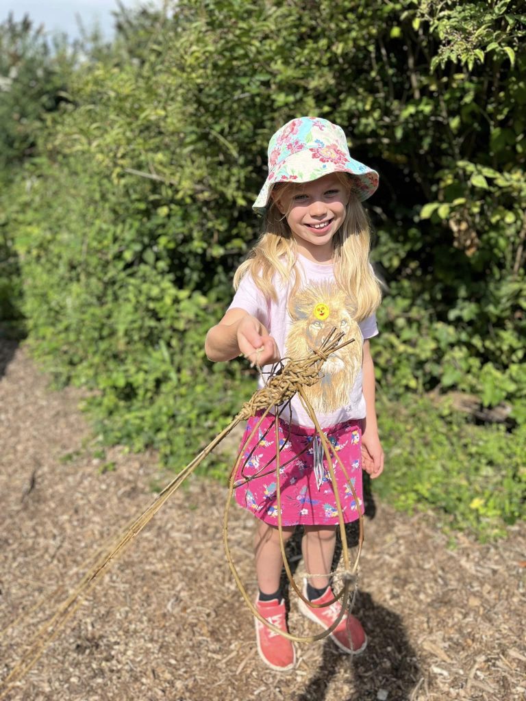 Child showing their willow dragonfly created with Weird Sticks CIC at Orchard Forest School