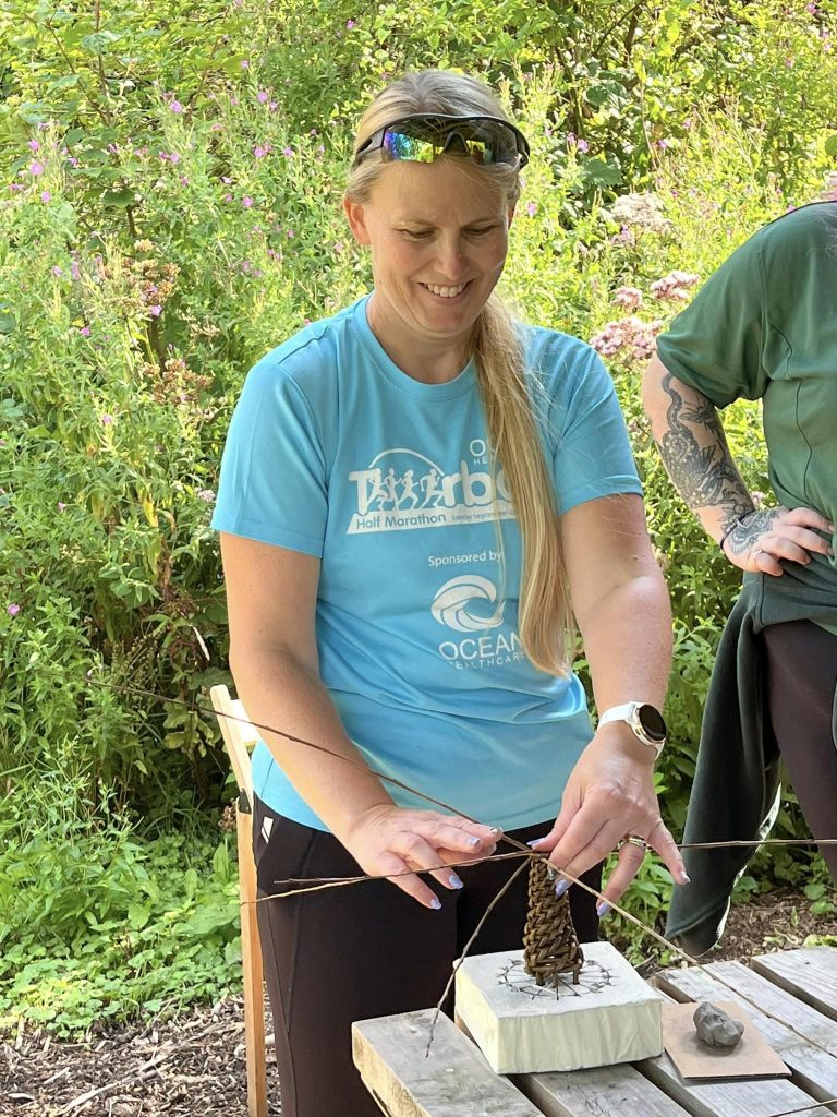 Adult creating a willow dragonfly with Weird Sticks CIC at Orchard Forest School 