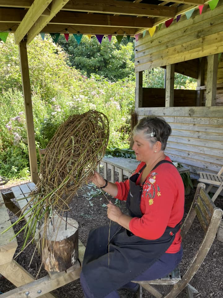 Vik from Weird Sticks CIC weaving an owl sculpture at Orchard Forest School 