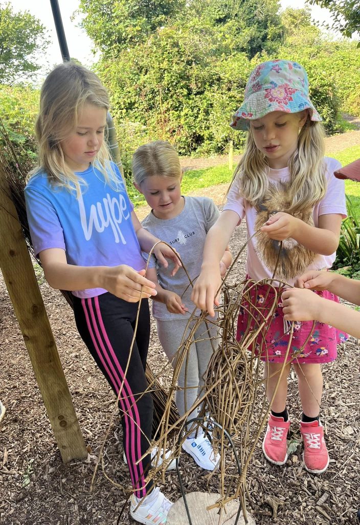 Children showing their willow creations made with Weird Sticks CIC at Orchard Forest School