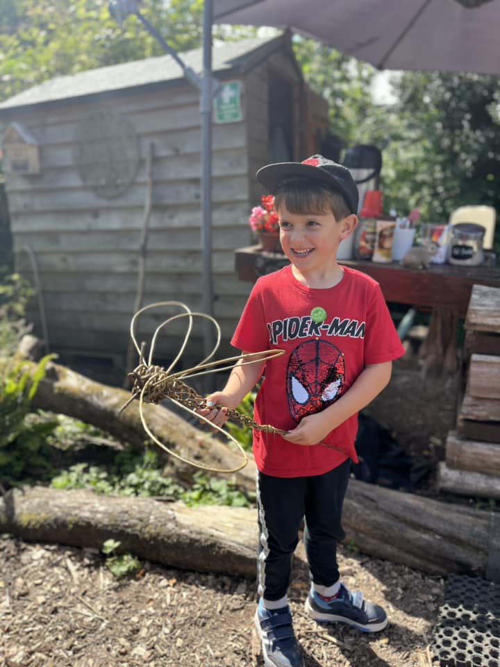 Child showing their willow dragonfly created with Weird Sticks CIC at Orchard Forest School