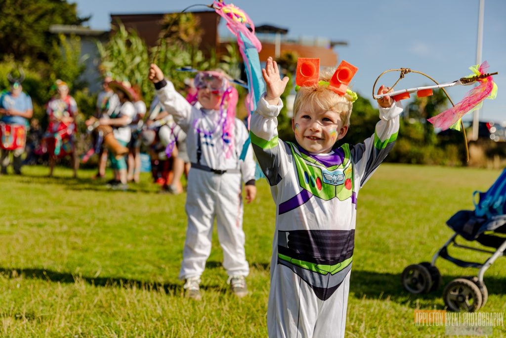 Children displaying their space-themed creations with Weird Sticks at the Exmouth Festival opening samba parade 2024