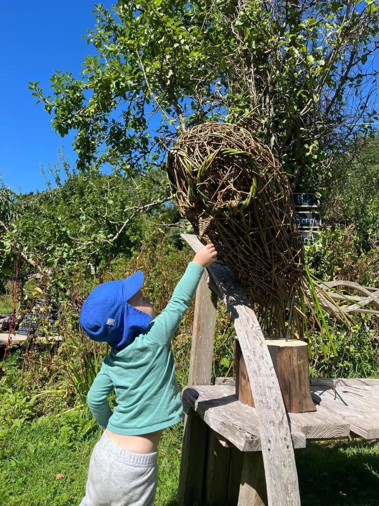 Small child with 'Ollie the Owl' sculpture created by Weird Sticks at Orchard Forest School 