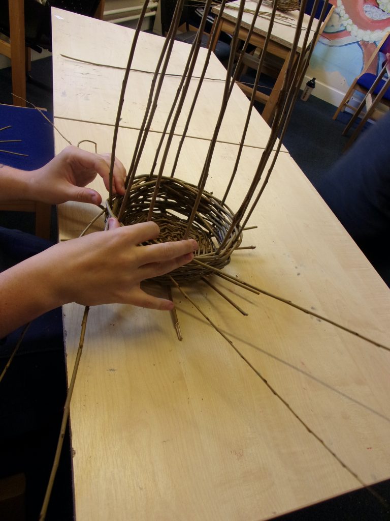 Willow baskets being woven by a participant at HMP Channings Wood during a Weird Sticks workshop as part of the Open Door Project