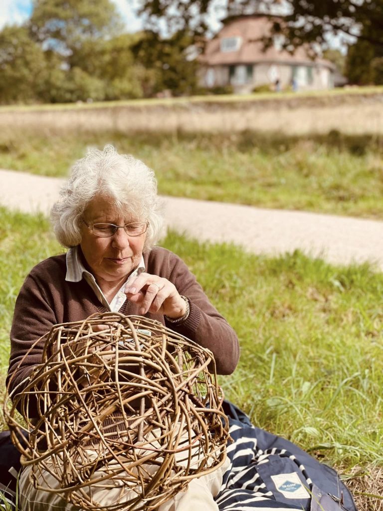 Participants weaving willow spheres for community ammonite sculpture created with Weird Sticks at A La Ronde