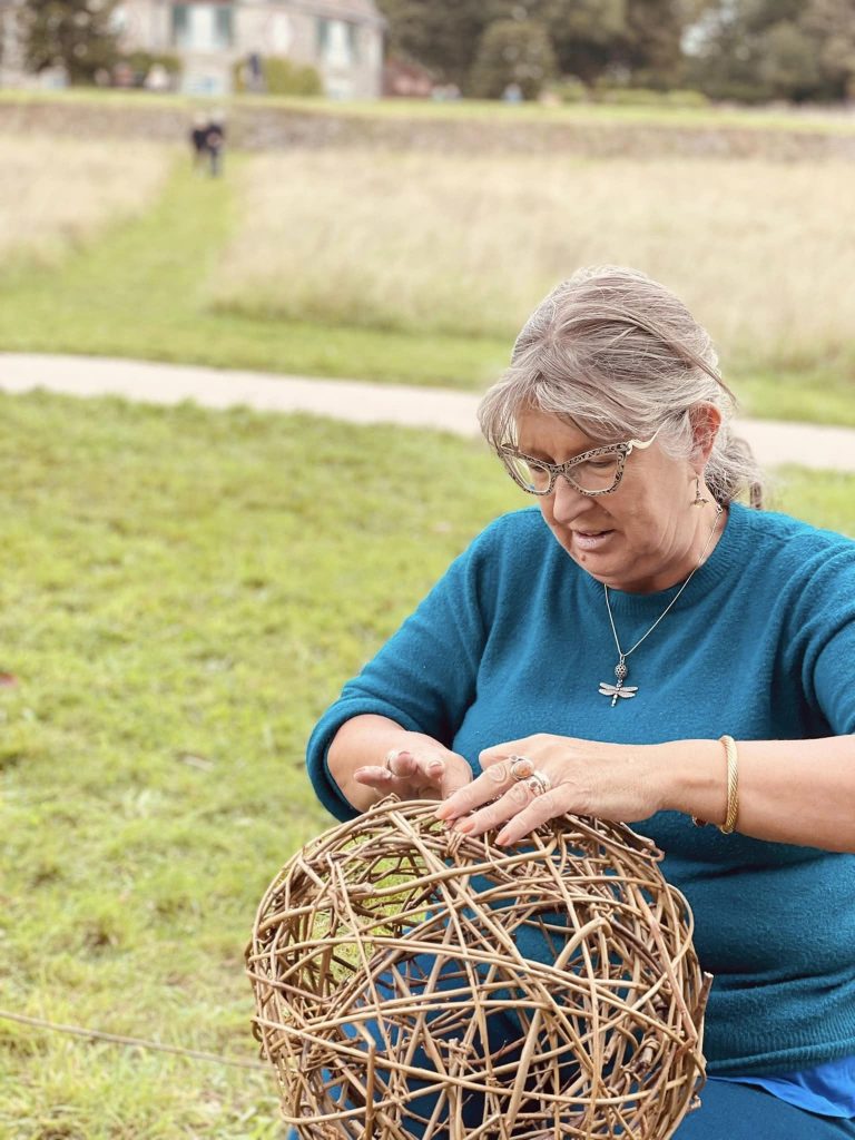 Participants weaving willow spheres for community ammonite sculpture created with Weird Sticks at A La Ronde