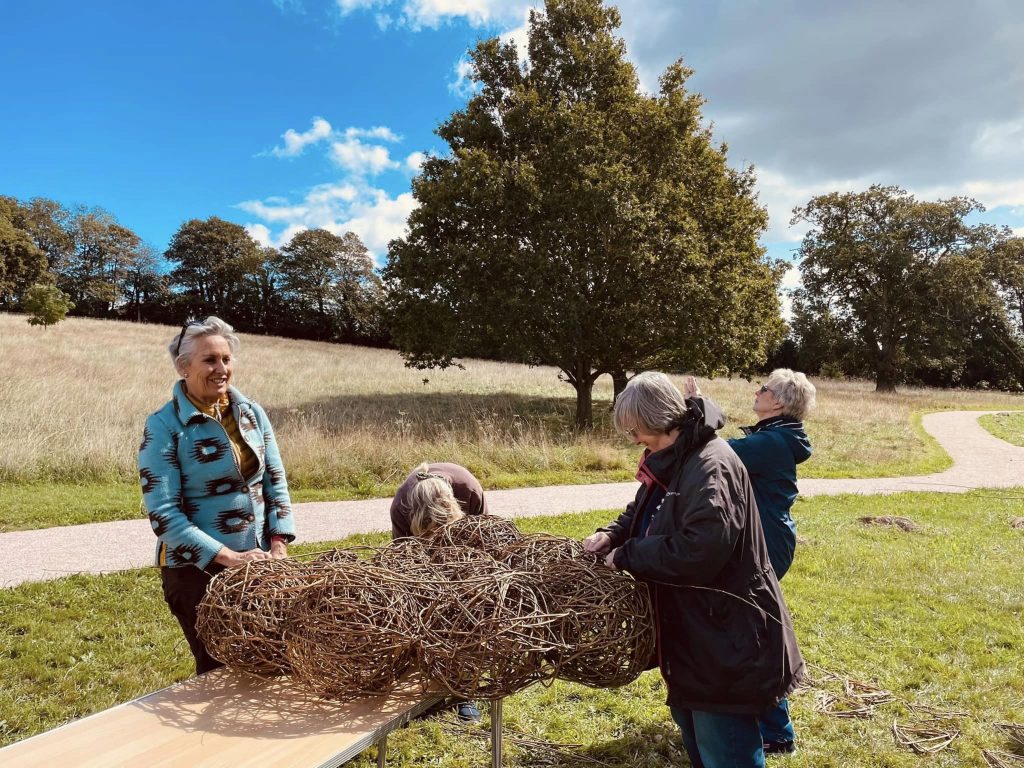 Participants weaving community ammonite sculpture created with Weird Sticks at A La Ronde