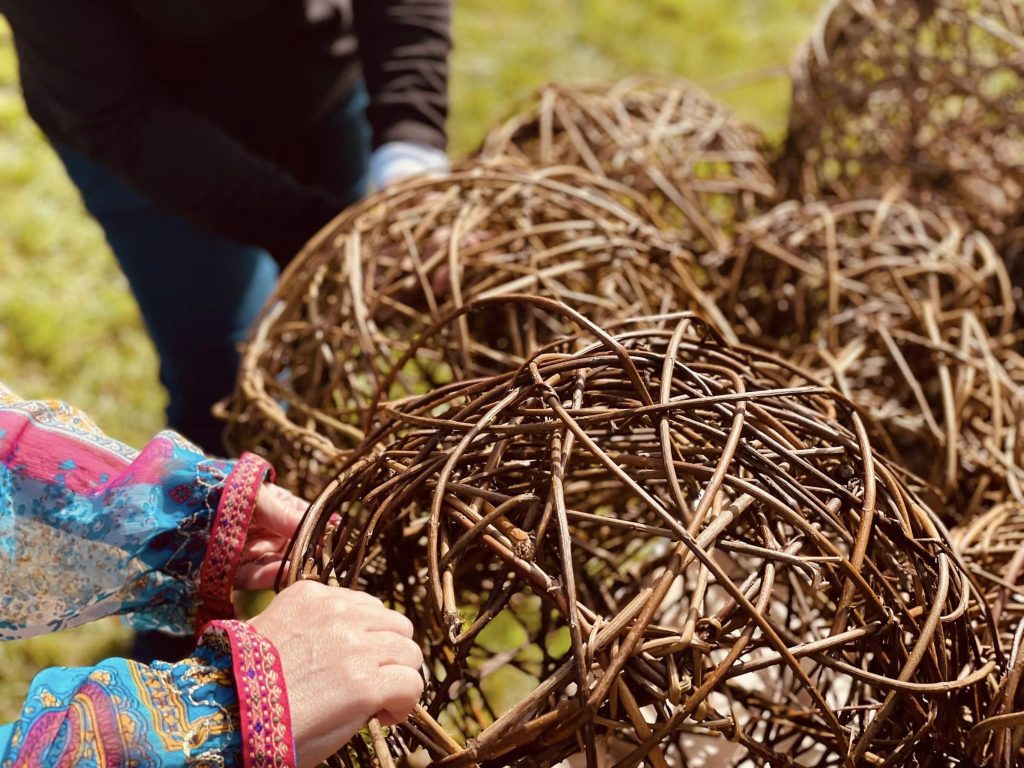 Participants weaving community ammonite sculpture created with Weird Sticks at A La Ronde