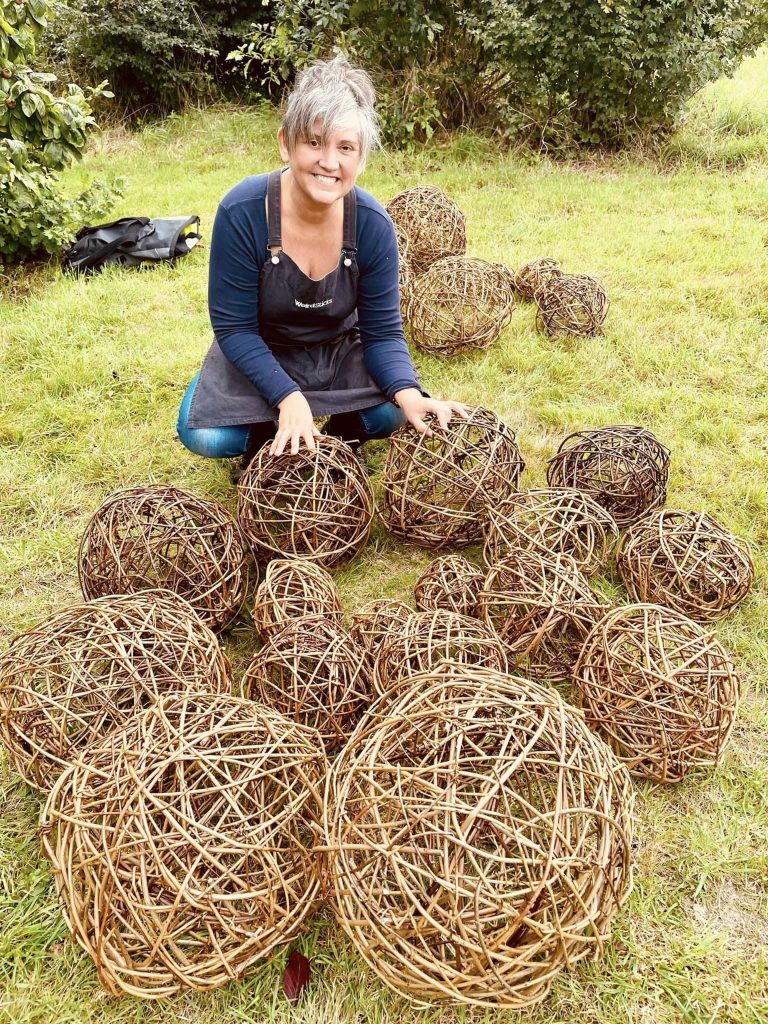 Vik from Weird Sticks with willow spheres woven for community ammonite sculpture at A La Ronde