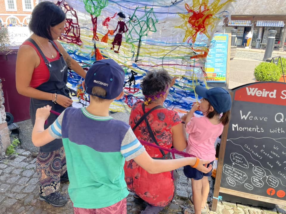 Children weaving to create 'Woven in Time' artwork with Weird Sticks at Exeter Quay