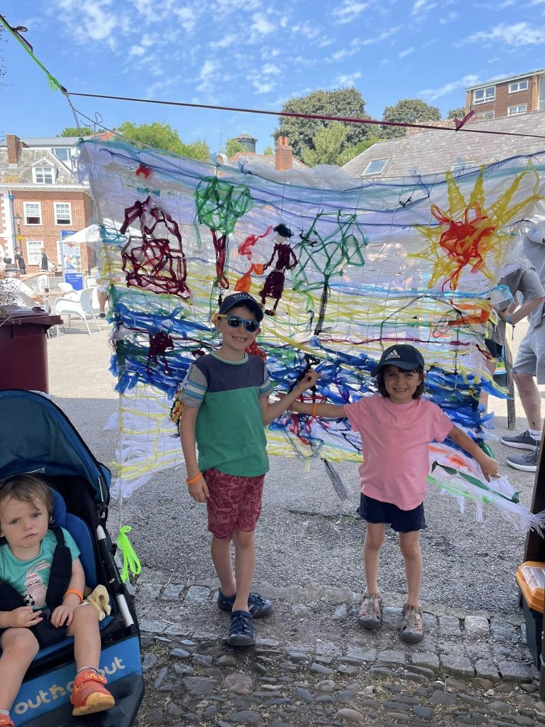 Children weaving to create 'Woven in Time' artwork with Weird Sticks at Exeter Quay