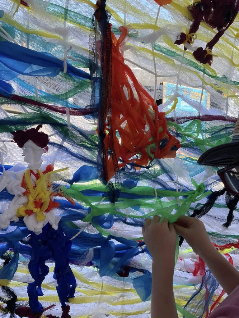 Children weaving to create 'Woven in Time' artwork with Weird Sticks at Exeter Quay