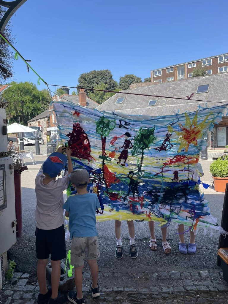 Children weaving to create 'Woven in Time' artwork with Weird Sticks at Exeter Quay